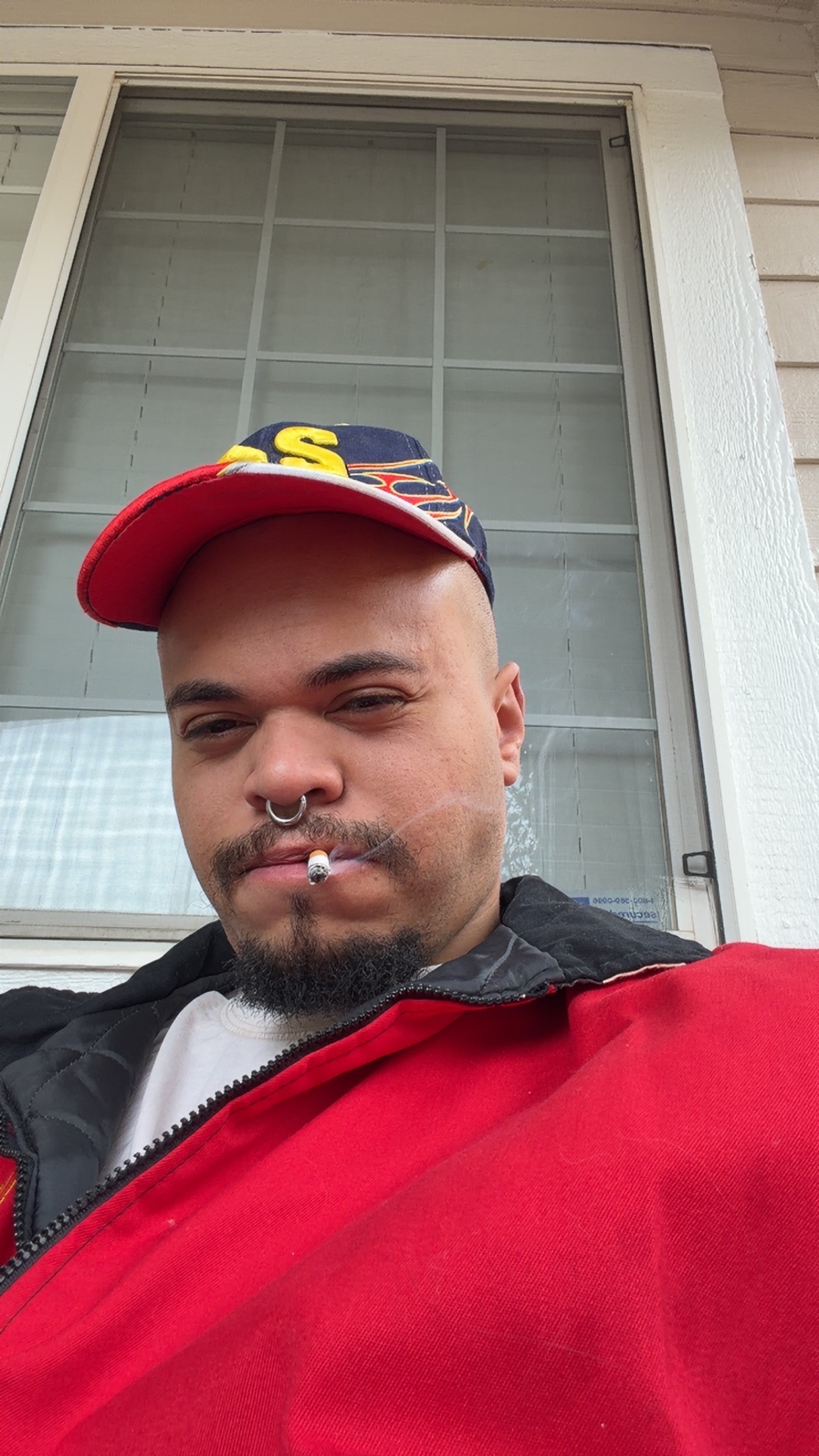 Porch selfie with cigarette and cap.